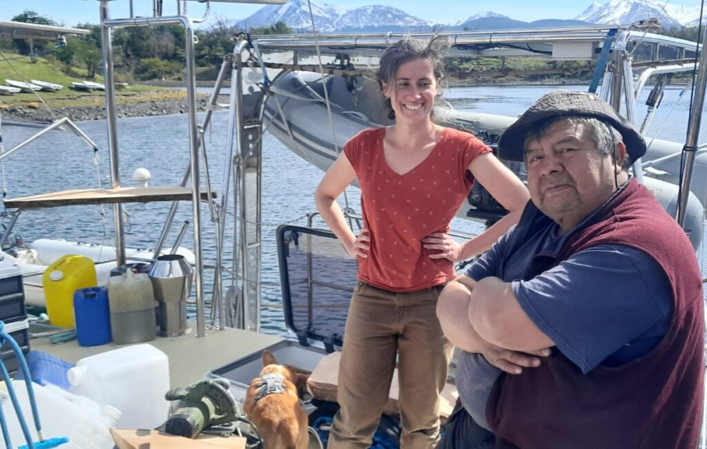 Lauriane et José à bord de Milagro, avec un premier plan de travail en bois de coigue sur le balcon arrière tribord.
